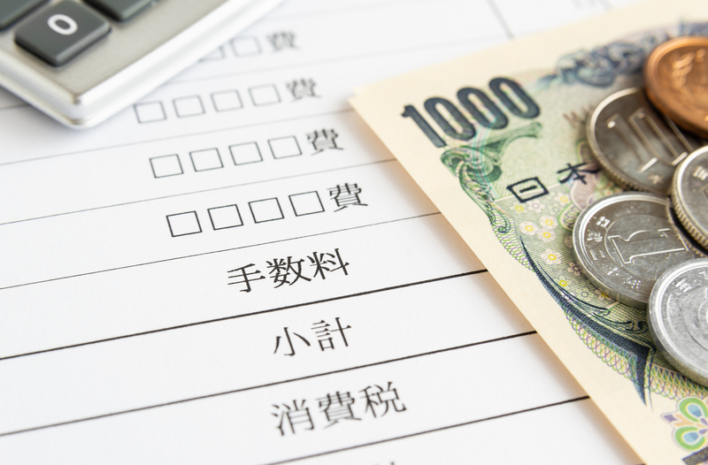 消費税や小計と書かれた紙の上に1000円札と貨幣と電卓