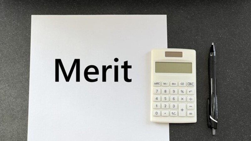 Meritと書かれた紙と電卓とペン