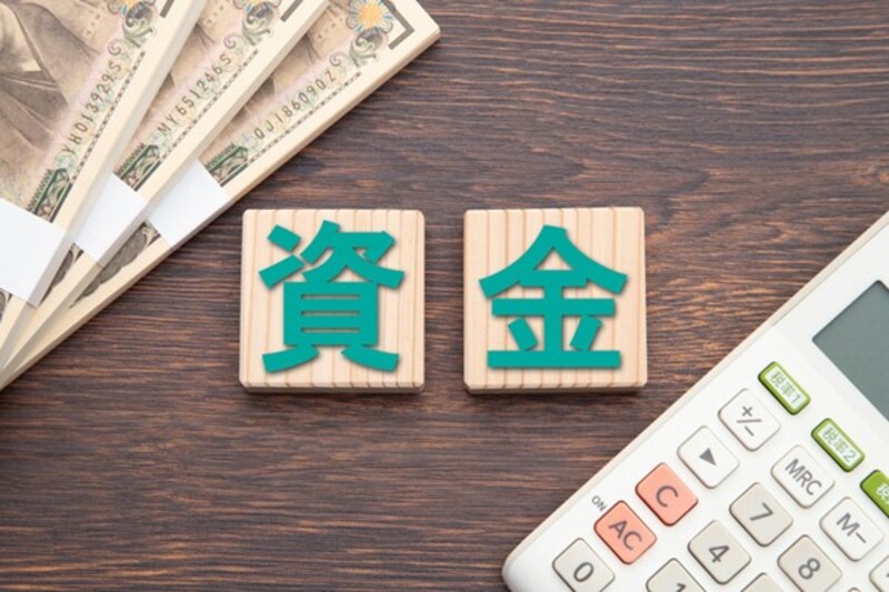 資金と書かれた木のブロックと電卓と100万円札束3束