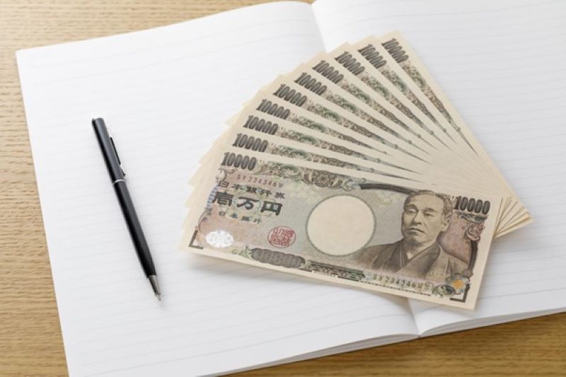 ノート上に置かれた1万円札とペン