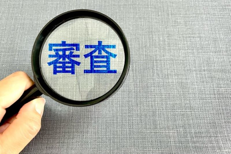 虫眼鏡で覗き込む「審査」の文字