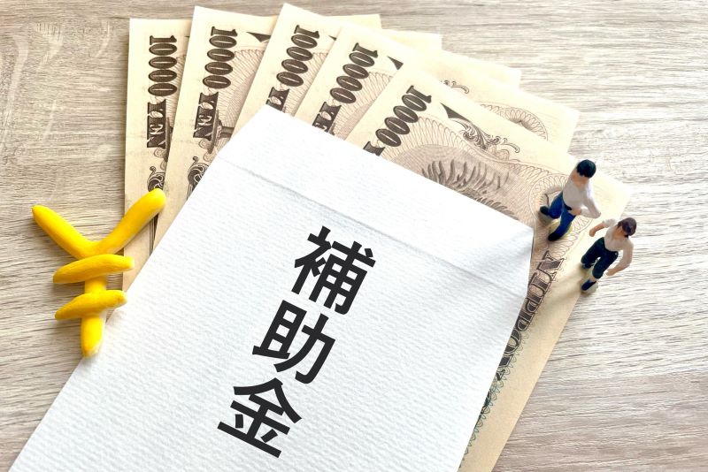 「補助金」と書かれた封筒と一万円札