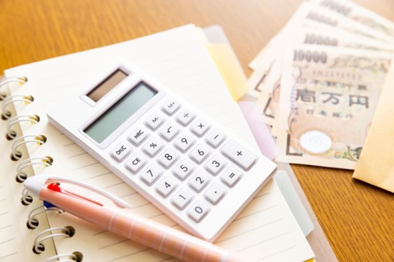 手帳上の電卓と封筒に入った一万円札