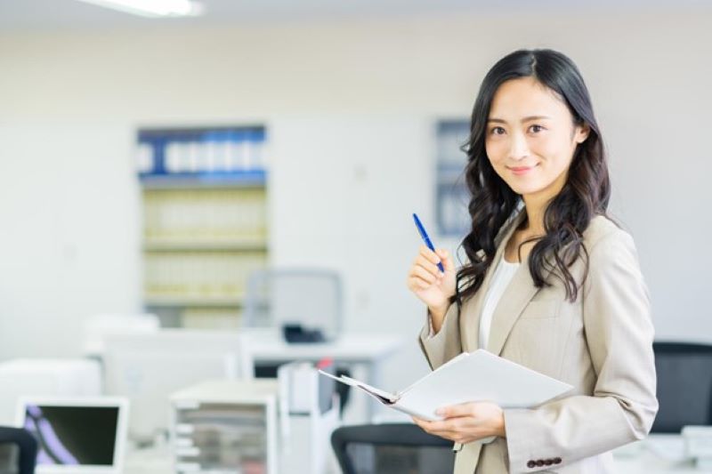 オフィスで手帳とペンを持つ女性