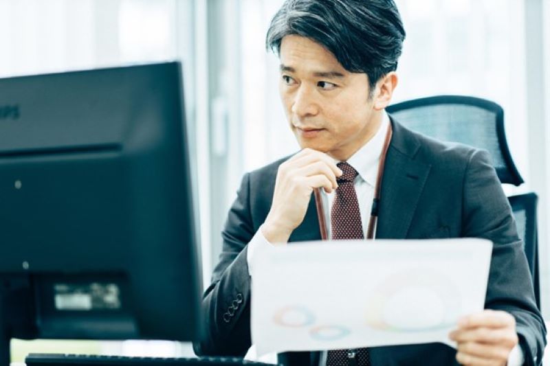 資料を見ながら考え込む男性