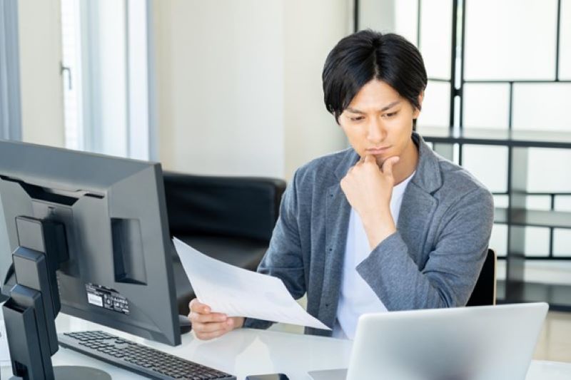 資料を見ながら考え込む男性