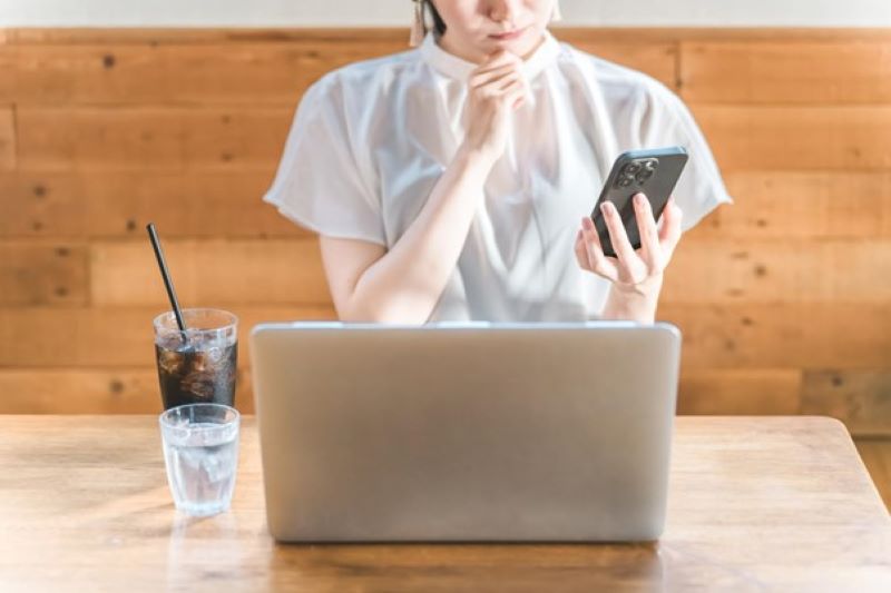 スマホ画面を見ながら考え込む女性