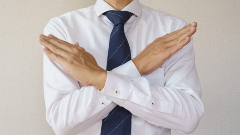 両手で×印をする男性