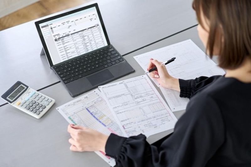 パソコンと資料を使い作業する女性