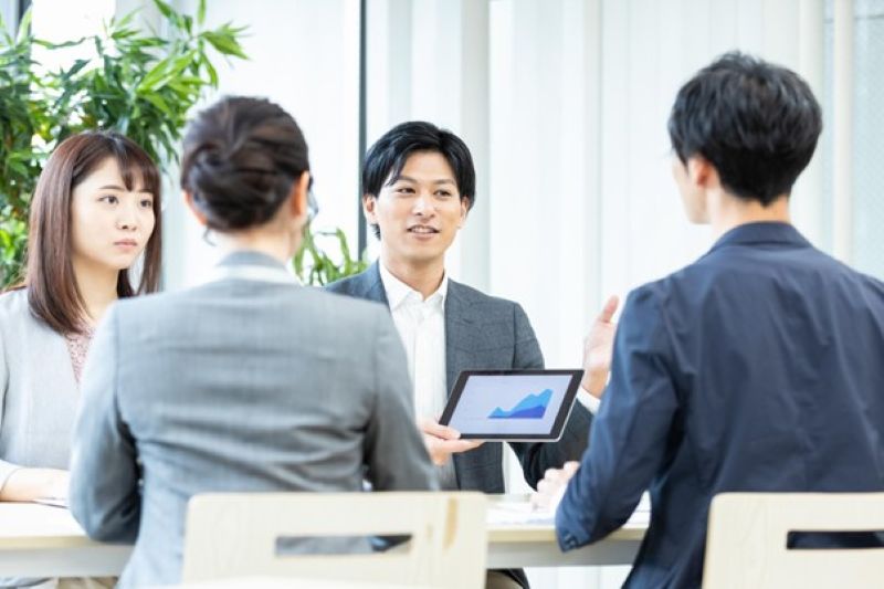 タブレットを使用し議論する4人の男女