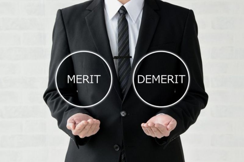 「MERIT」「DEMERIT」と書かれた円図を両手に浮かべた男性