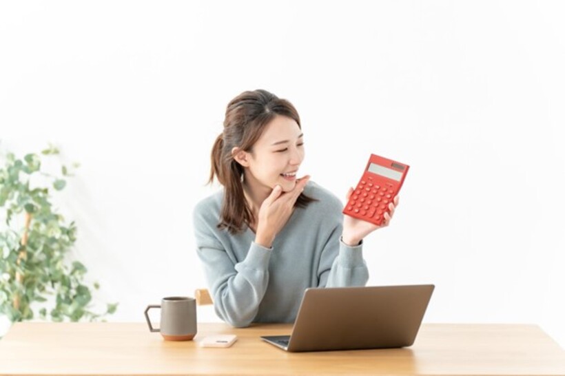 パソコンの前で電卓を持つ女性